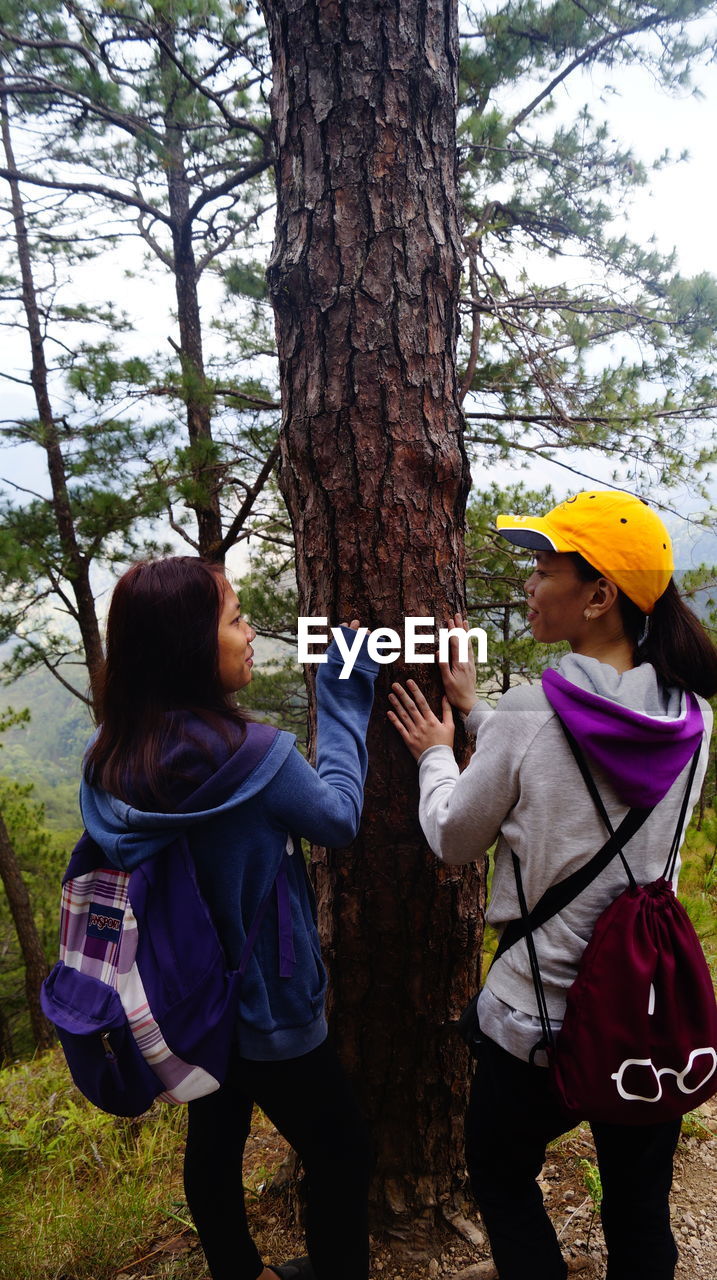 WOMEN STANDING ON TREE TRUNK