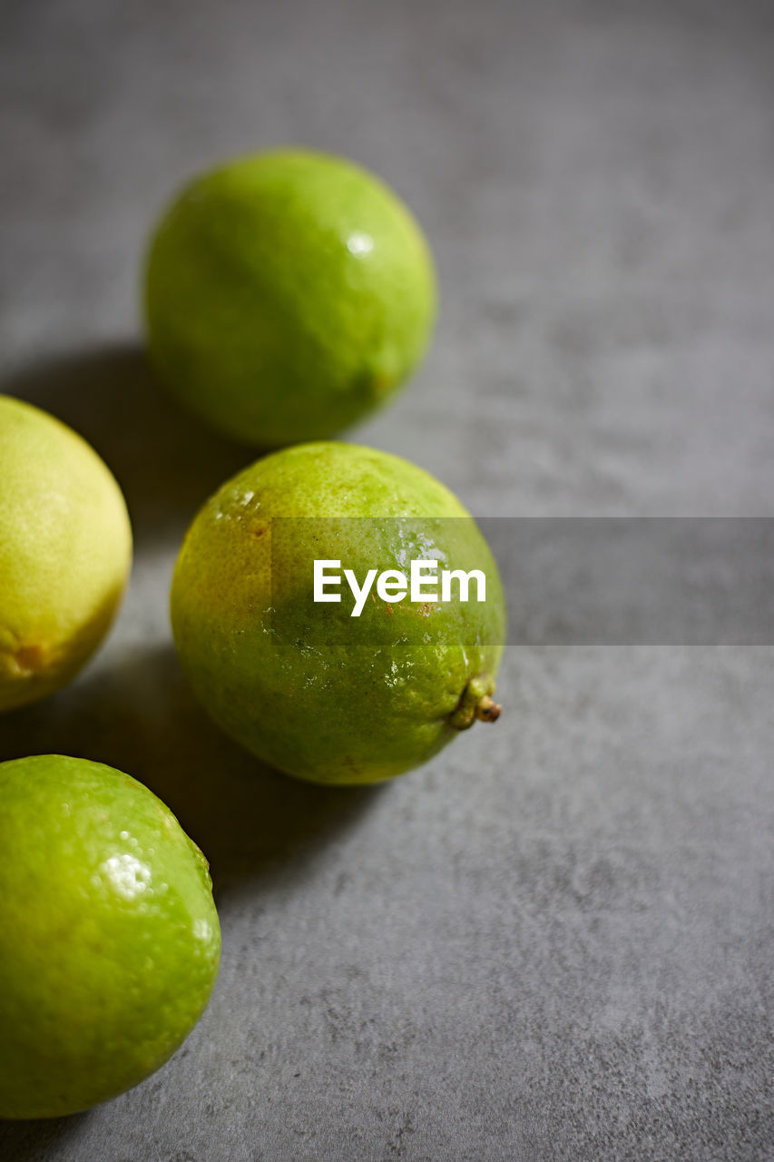 lime, healthy eating, citrus, green, food and drink, food, fruit, freshness, wellbeing, lemon, plant, produce, citrus fruit, yellow, no people, studio shot, indoors, close-up, macro photography, group of objects, still life, gray background, focus on foreground, gray, drink, citron, leaf, organic