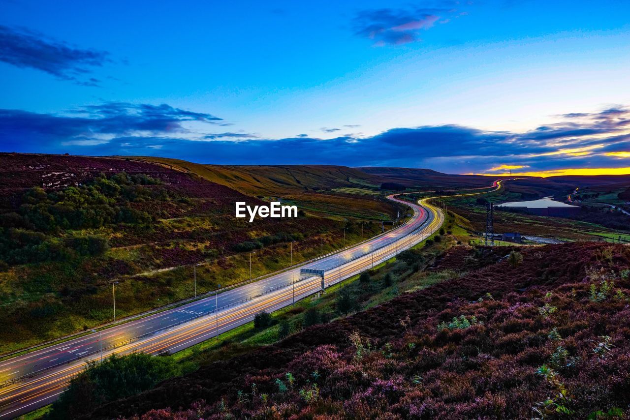 High angle view of winding road on landscape against blue sky