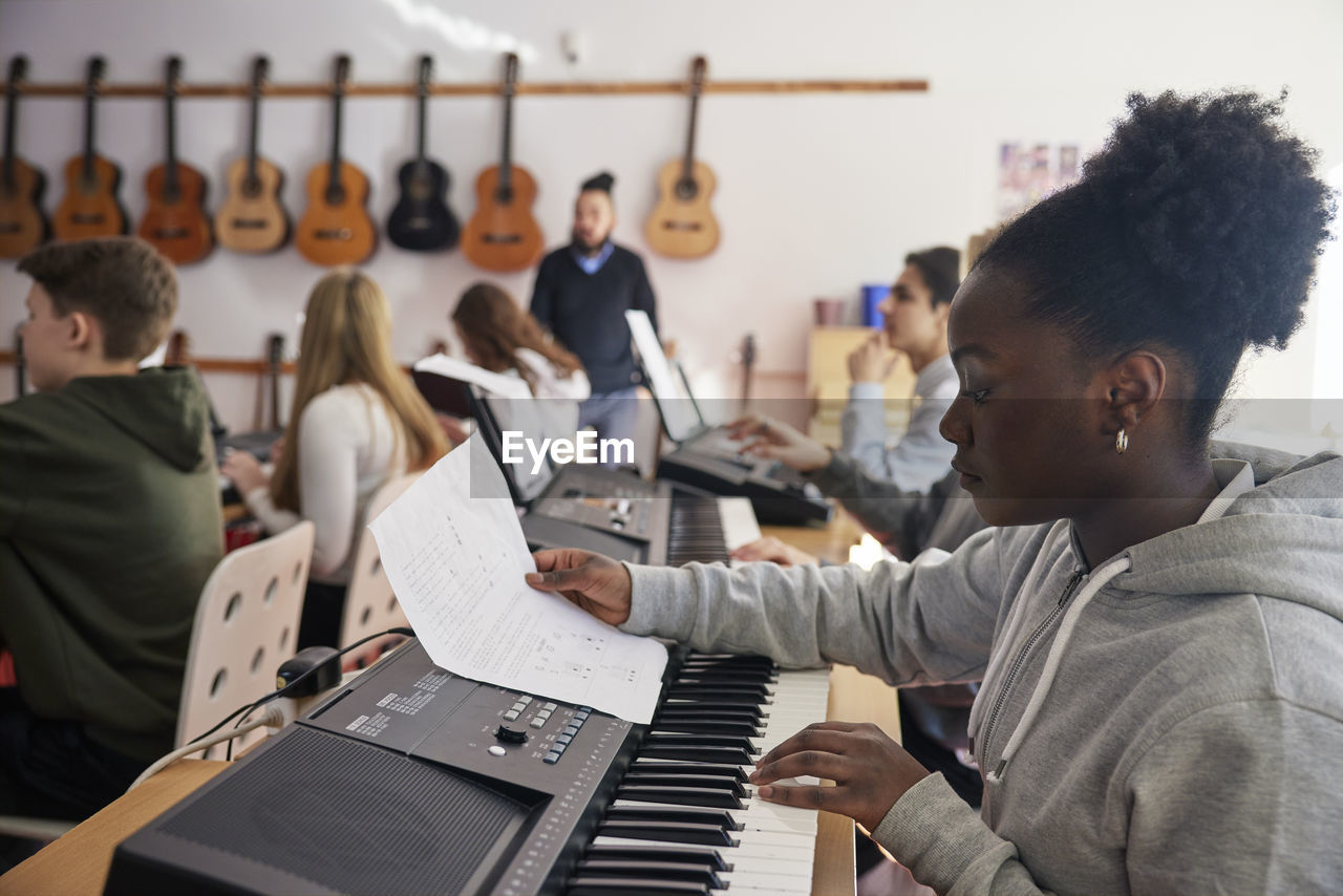 Teenagers attending keyboard lesson
