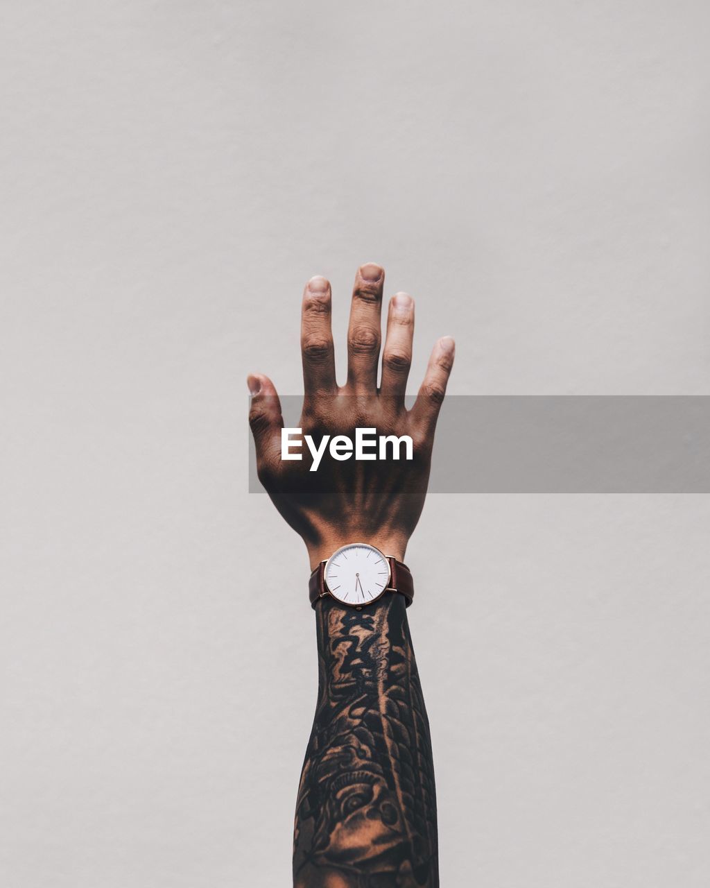 Cropped image of man hand with tattoo wearing wrist watch against white background