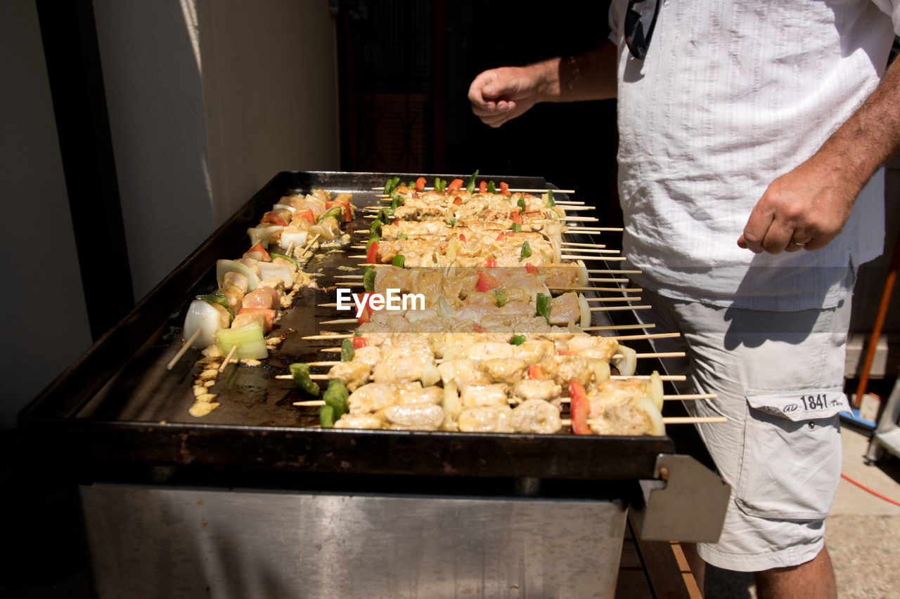 Midsection of man cooking chicken on barbecue grill