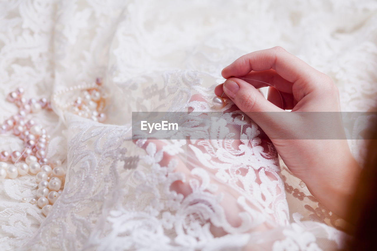 Cropped hands of woman stitching wedding dress