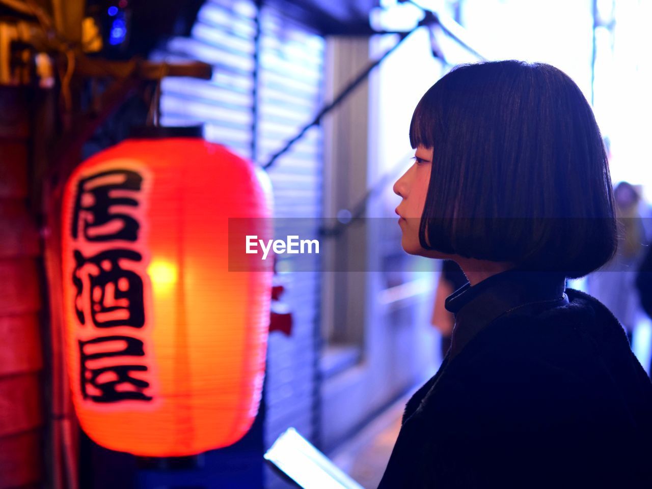 Side view of woman by chinese lantern in city 