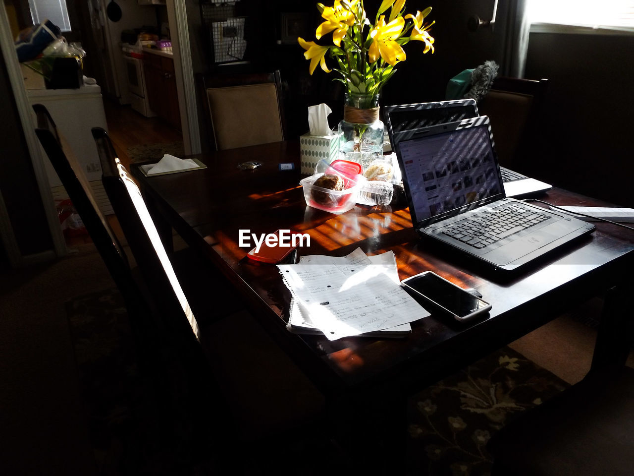 Laptop and mobile phone with documents on table at home
