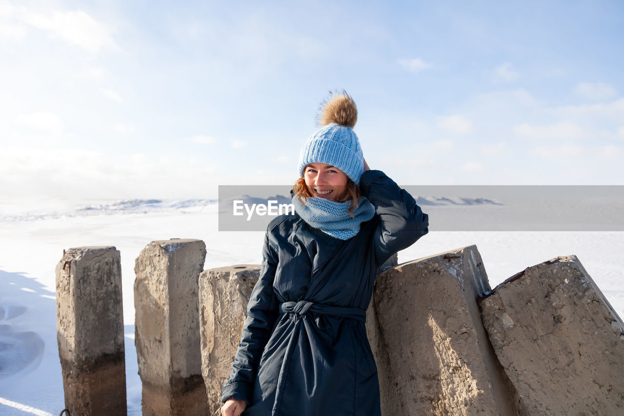 Close up portrait of beauty woman in frosty stylish coat around frozen sea and stone 