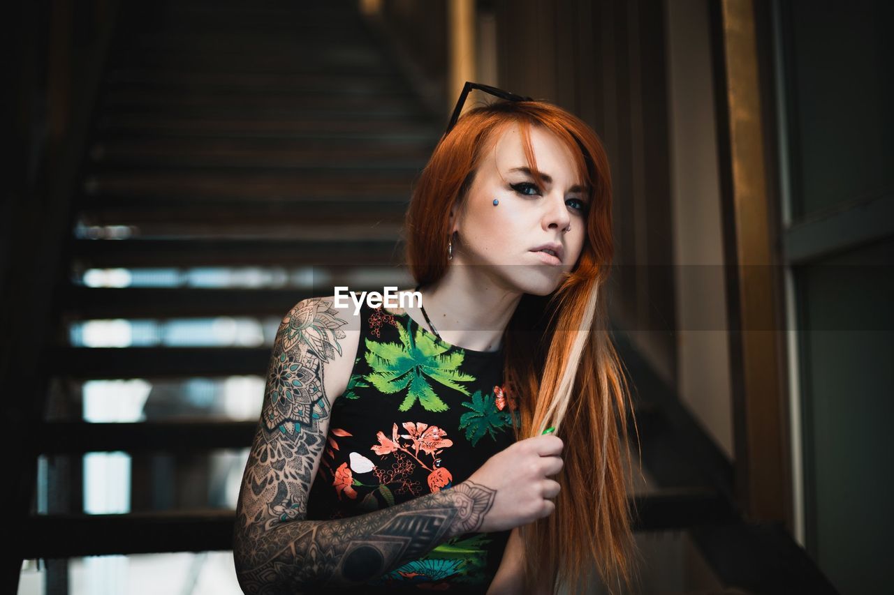 Portrait of tattooed young woman at home