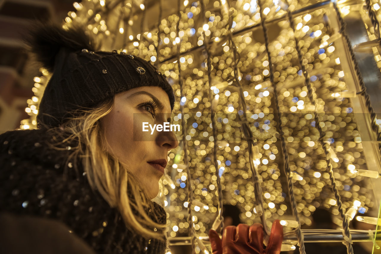 A young girl in a hat looking through christmas lights