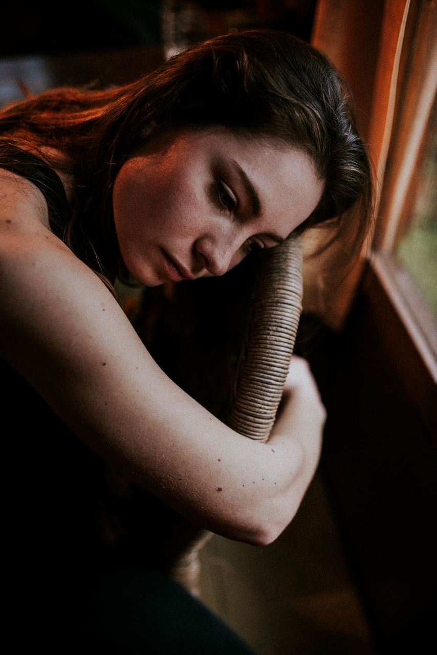 High angle view of thoughtful woman sitting on chair by window at home