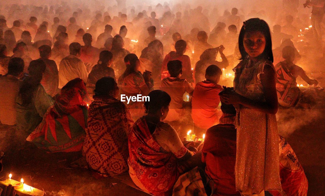 A girl is looking at camera while people are praying at rakher upobash