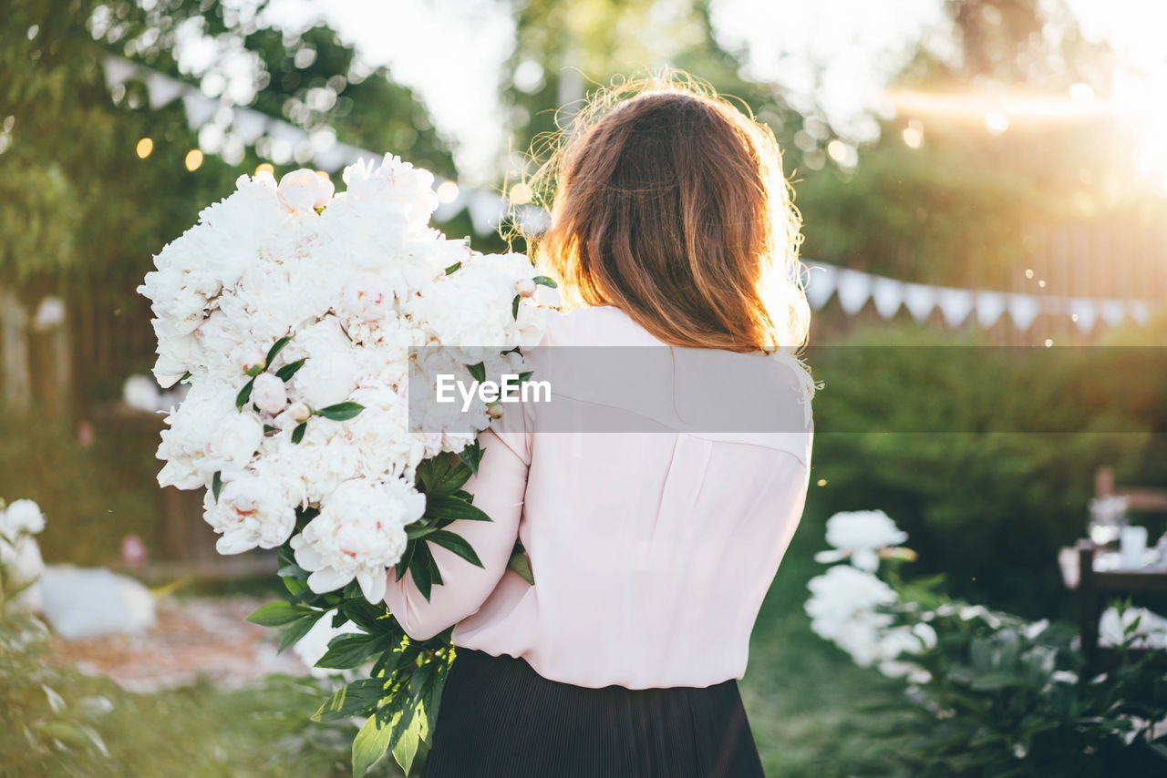 rear view of woman standing by flowering plant