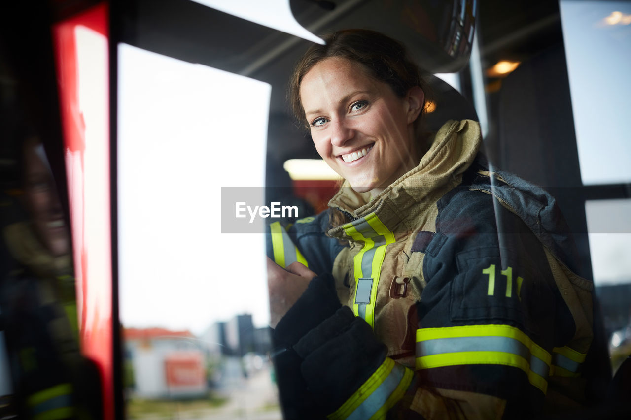Portrait of smiling female firefighter sitting in fire engine
