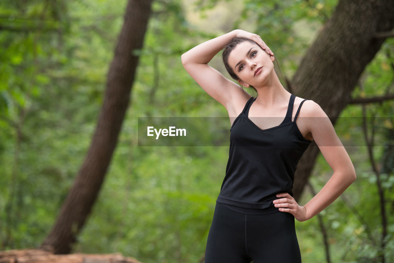 portrait of young woman standing against tree