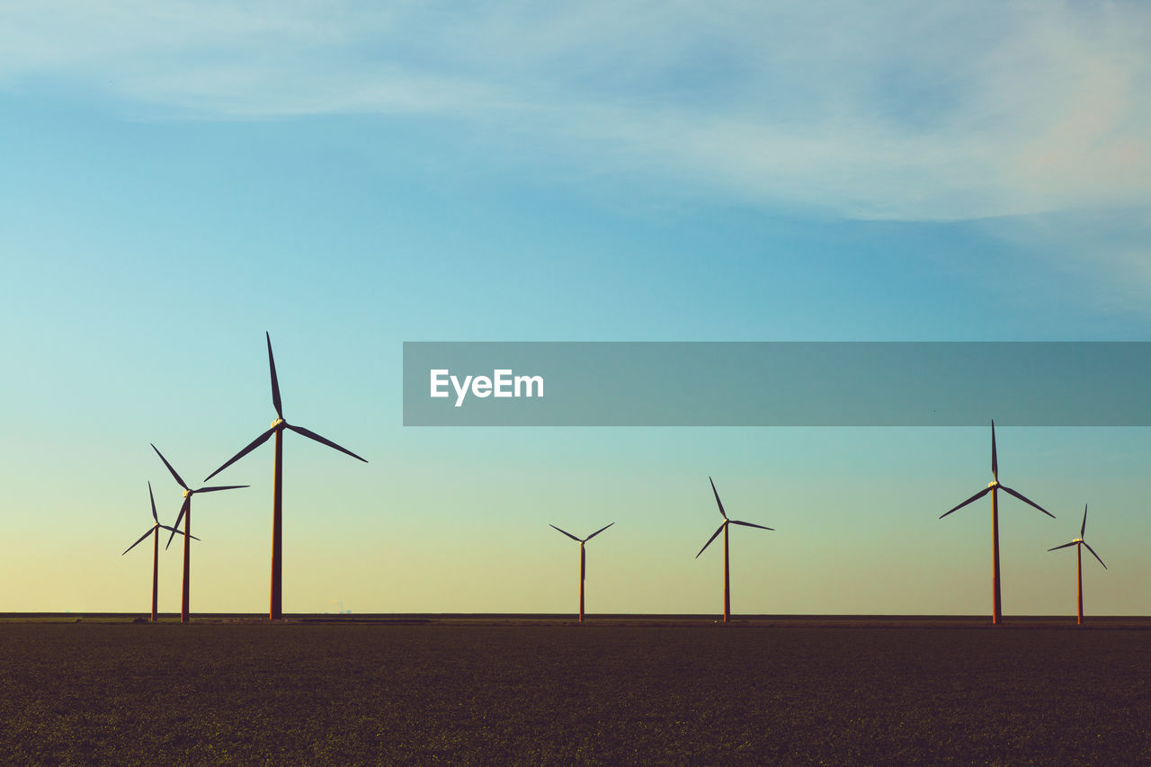 Windmills on field against sky