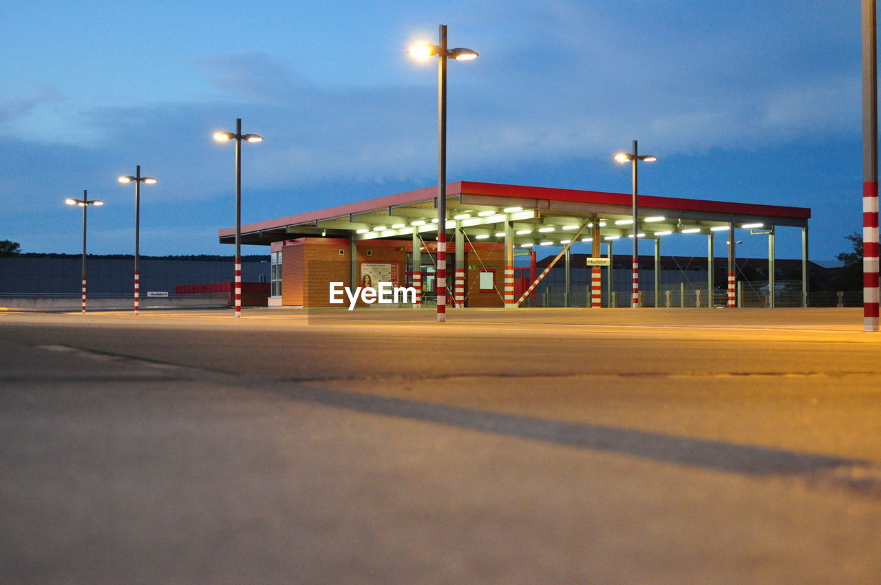 Illuminated empty parking lot against sky at dusk