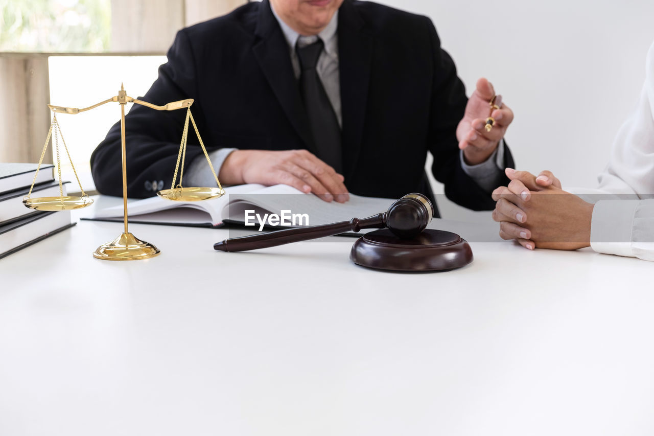 Midsection of male lawyer discussing with customer at desk