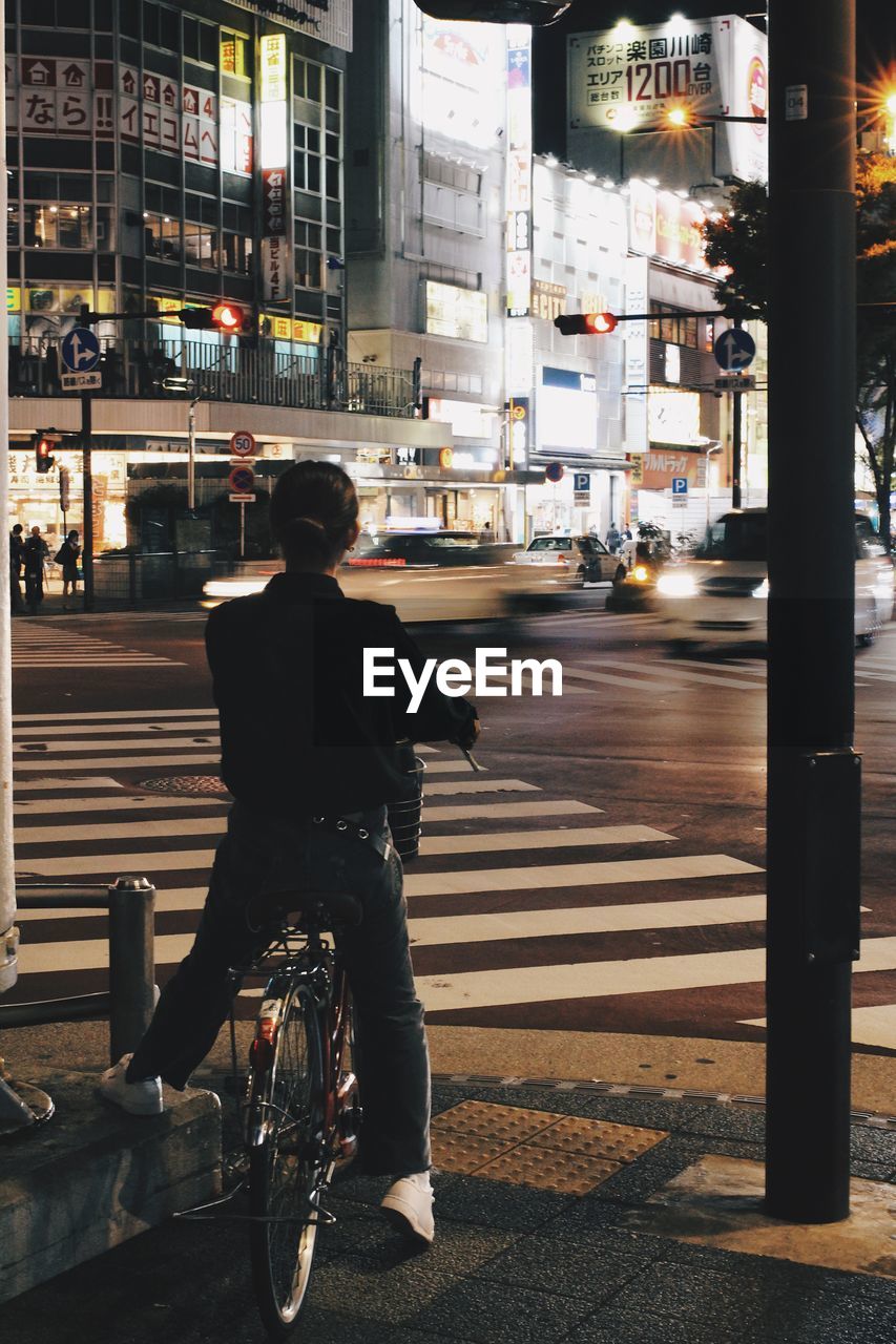 MAN RIDING BICYCLE ON ROAD AT NIGHT