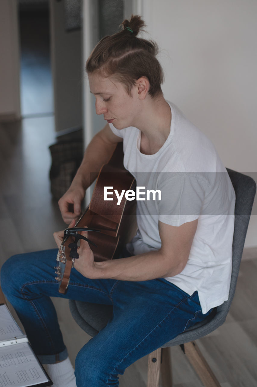 Casual-looking blond boy with freckles spends his free time playing his memorial guitar and singing