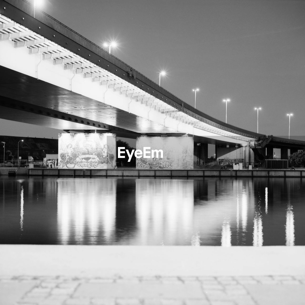 Illuminated bridge over river against sky at night