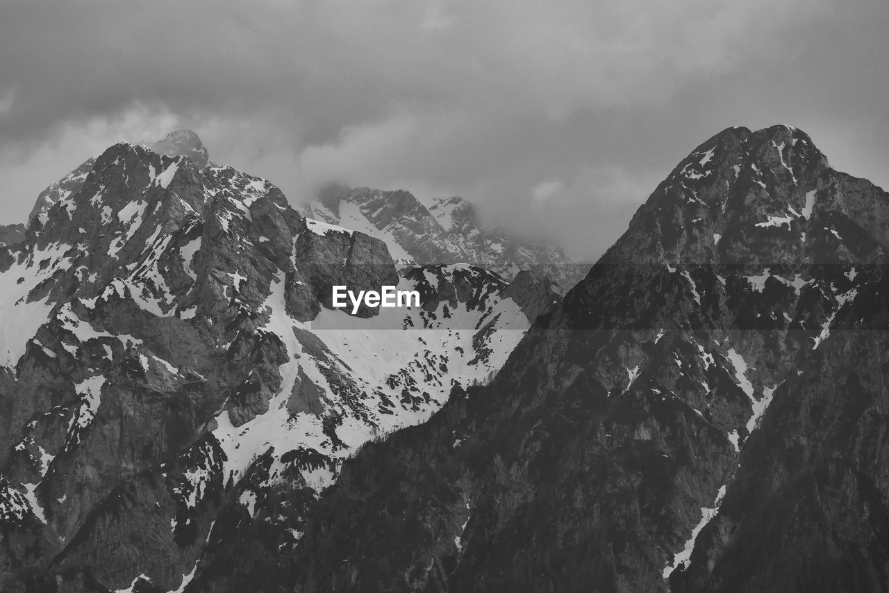 mountain, mountain range, scenics - nature, black and white, sky, cloud, environment, landscape, beauty in nature, monochrome, mountain peak, snow, monochrome photography, nature, snowcapped mountain, rock, travel destinations, cold temperature, travel, winter, no people, summit, land, outdoors, panoramic, ridge, tranquility, non-urban scene, extreme terrain, tranquil scene, tourism, activity, day, physical geography, high up, leisure activity, adventure