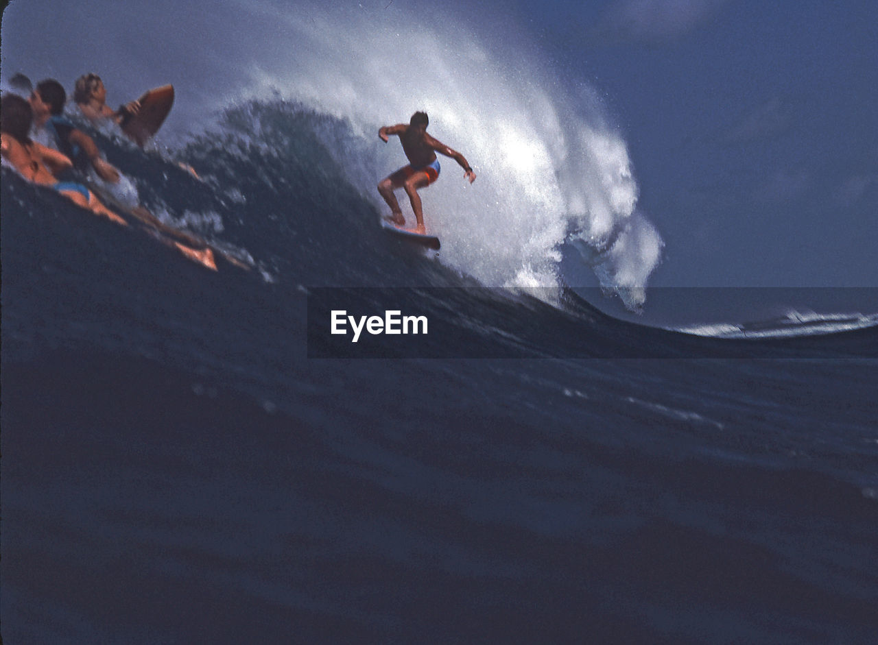 FULL LENGTH OF MAN SURFING ON SHORE