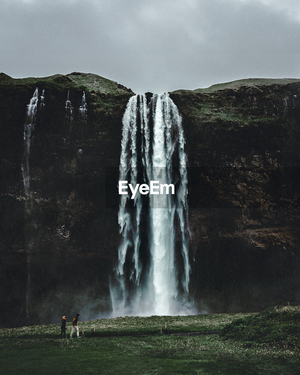 Friends standing against waterfall