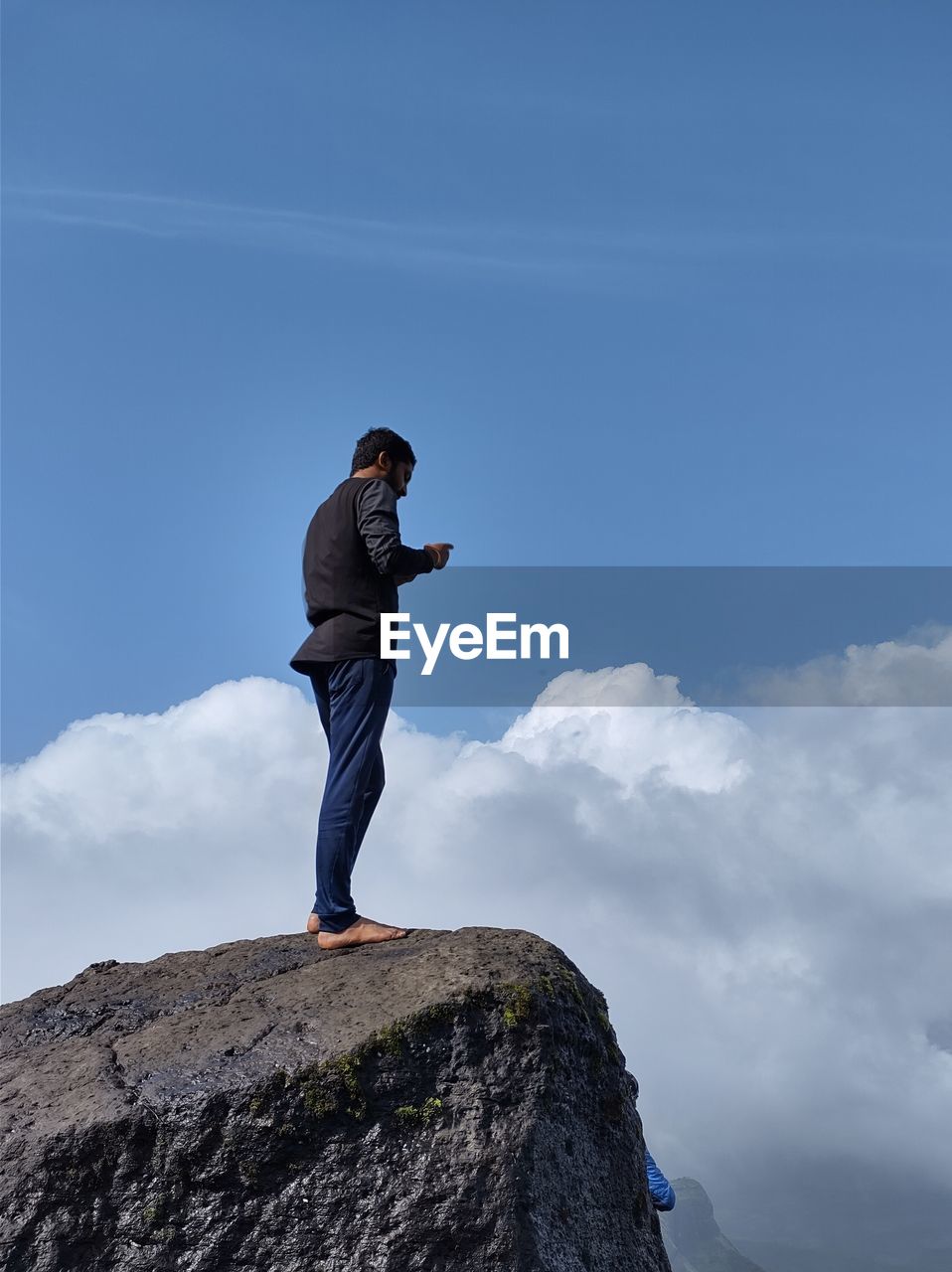 Man standing on rock against sky