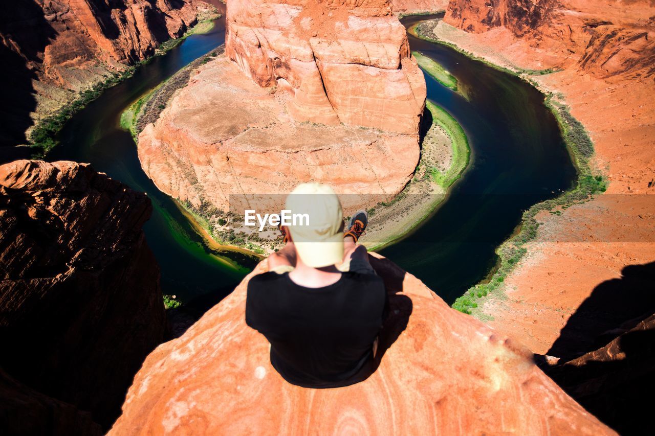 Rear view of man sitting on rock