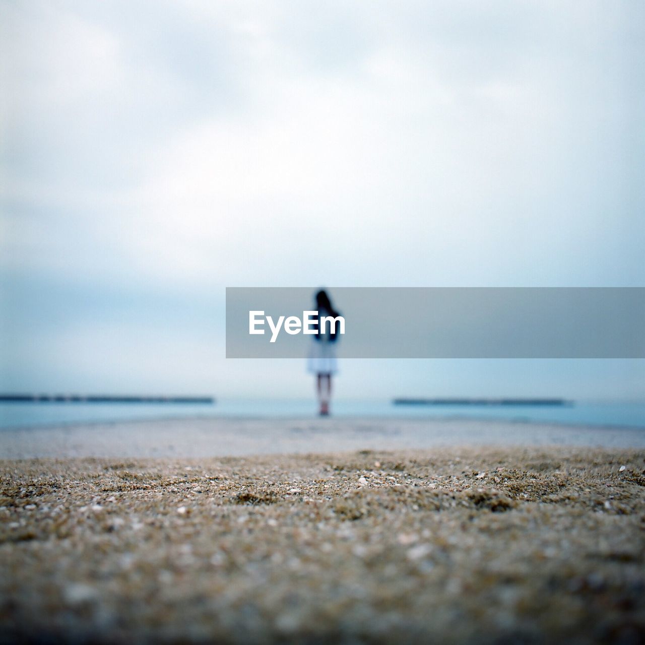 Woman standing at beach against sky