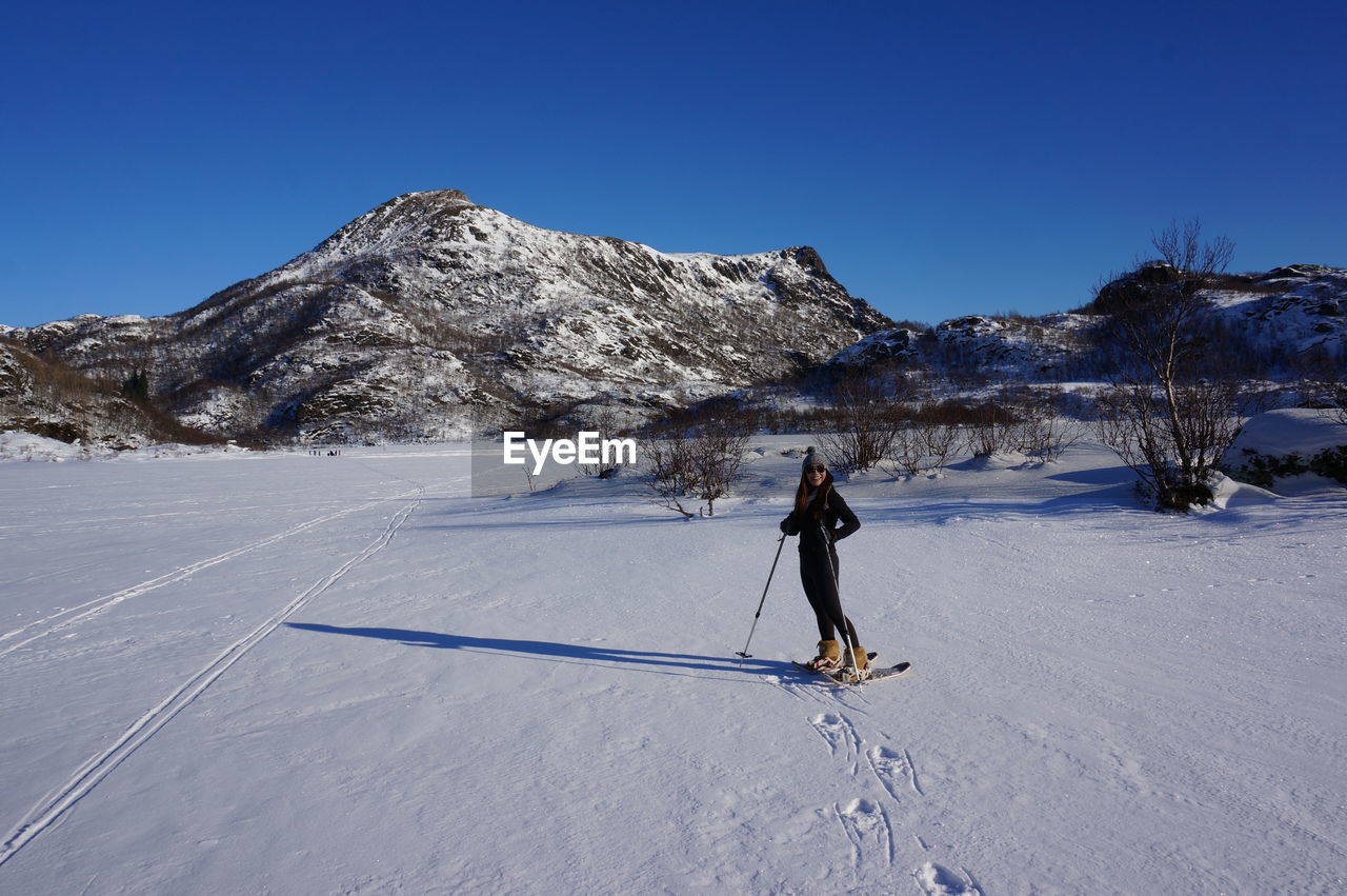 Full length of woman standing on snow covered field