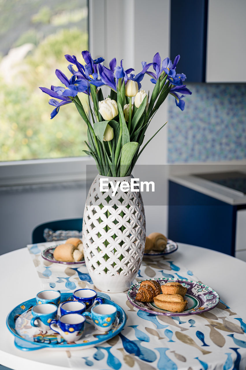 Close-up of breakfast and flower vase on table