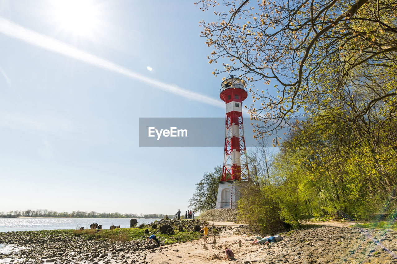 sky, tower, nature, sunlight, water, tree, lighthouse, plant, land, day, architecture, built structure, beach, outdoors, sunny, scenics - nature, sea, beauty in nature, no people, travel destinations, cloud, clear sky, environment, tranquility, travel, non-urban scene, landscape