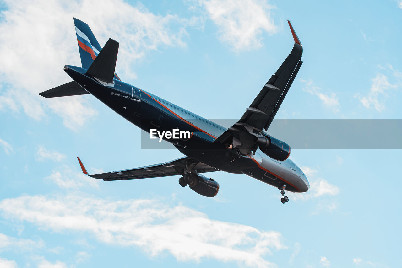 LOW ANGLE VIEW OF AIRPLANE IN MID-AIR AGAINST SKY