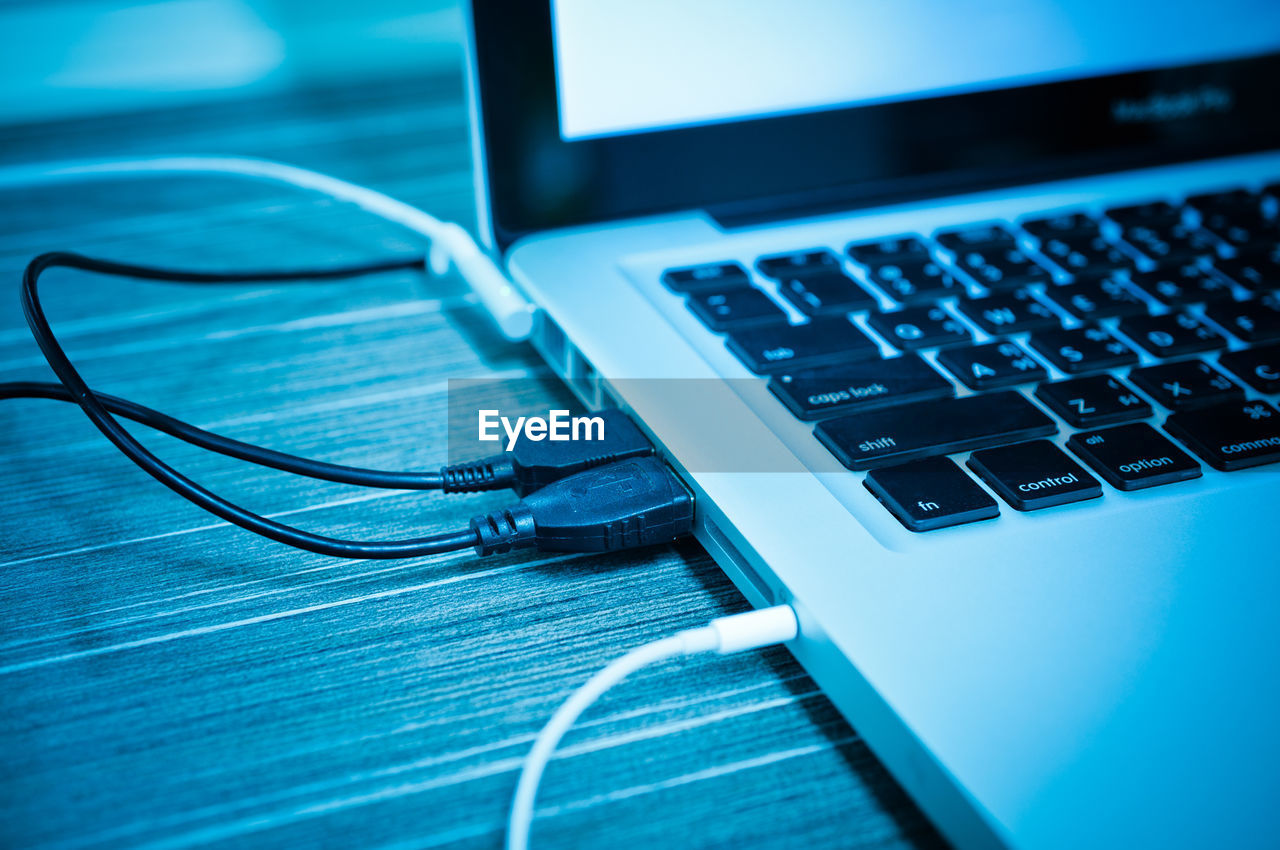 High angle view of usb cables attached to laptop on table