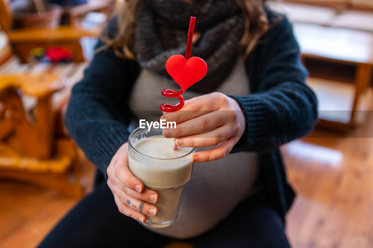 Midsection of woman drinking milk shake at cafe