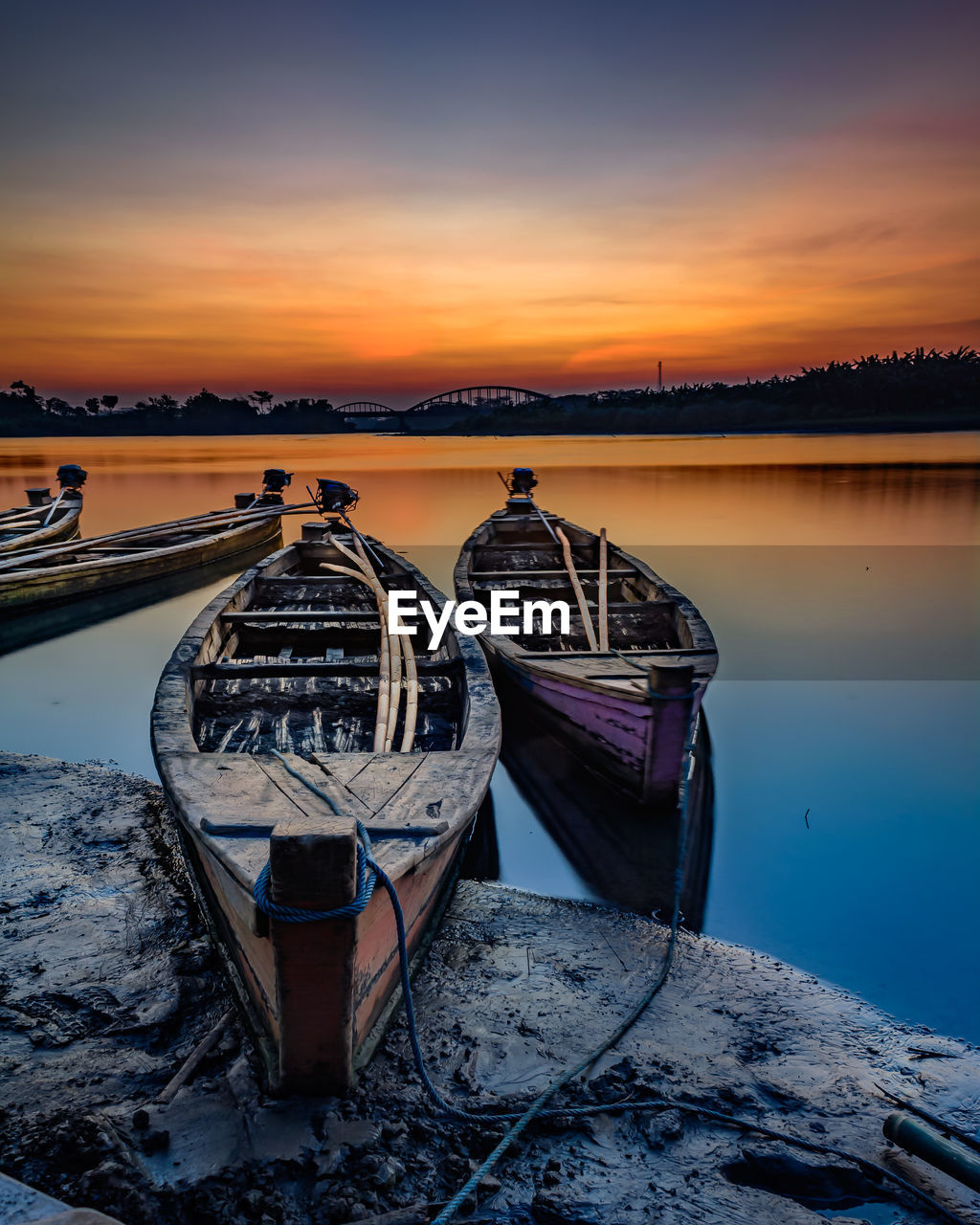 Boat moored on beach against sky during sunset