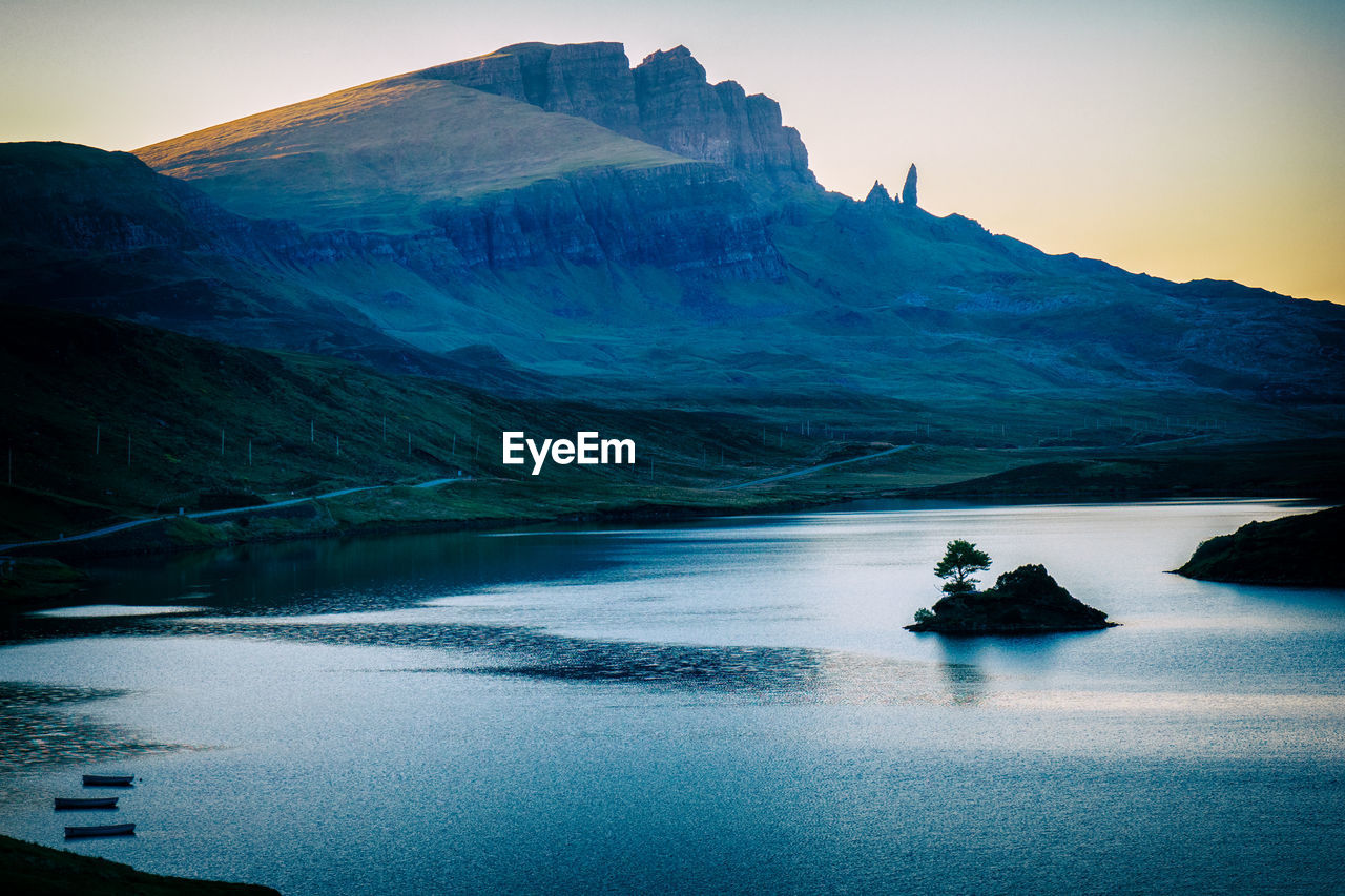 Lake in the majestic scottish highlands with small island, three boats and a small highway