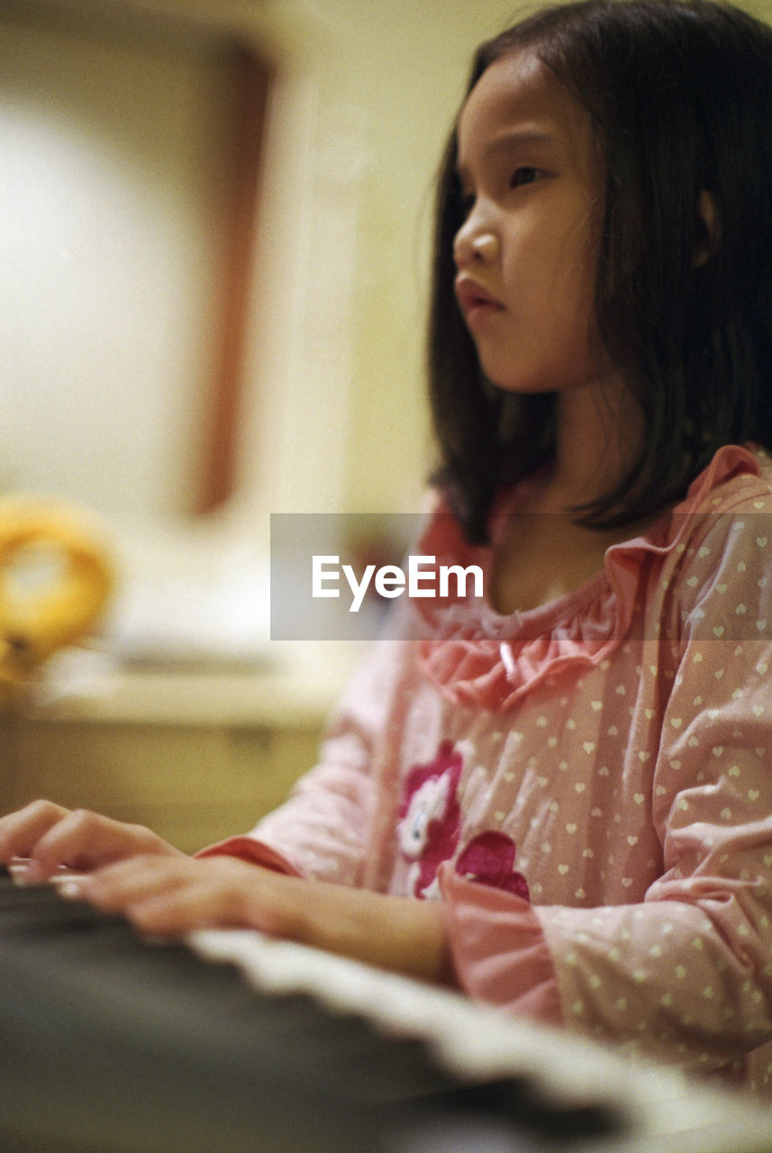 Portrait of child girl playing piano sitting at home