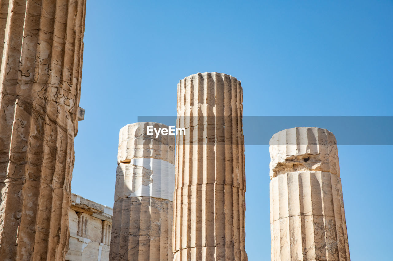 Low angle view of old columns against clear blue sky