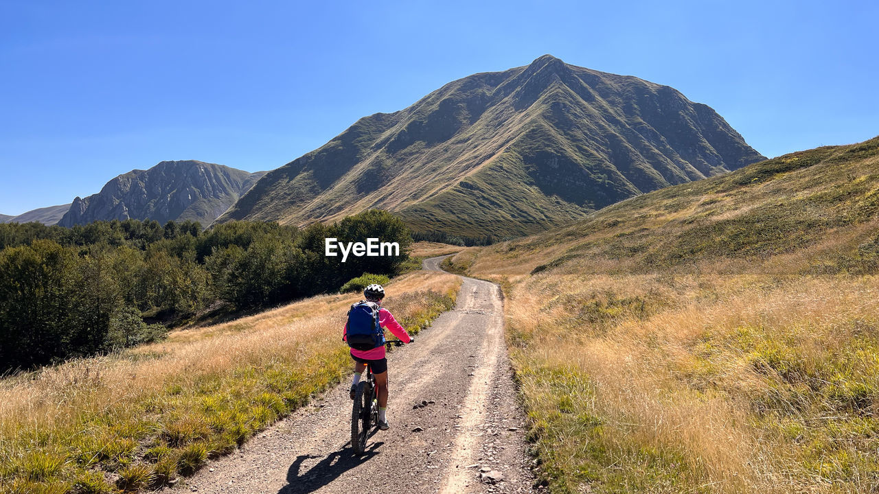 rear view of man walking on mountain against clear sky