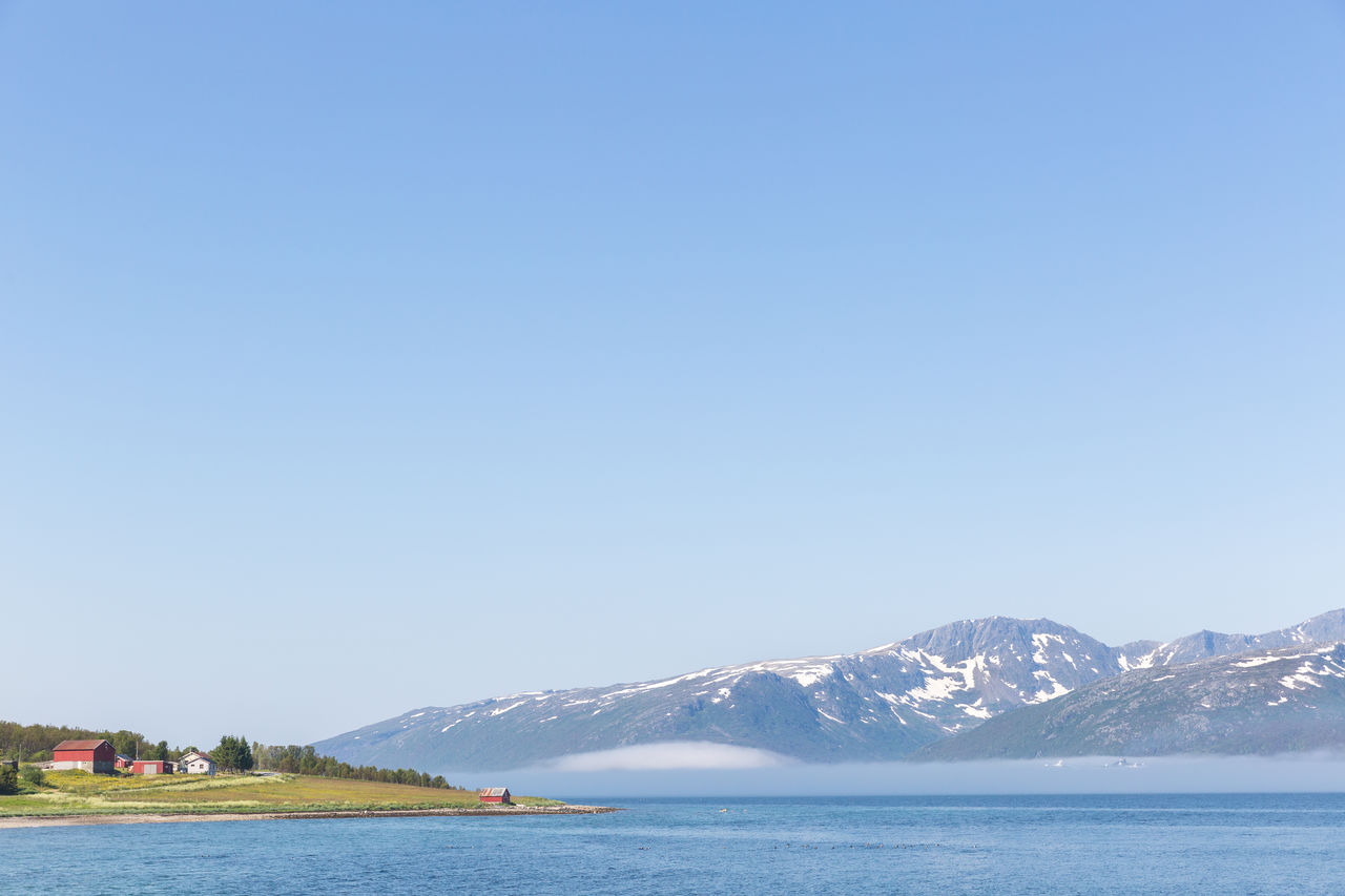 Scenic view of sea and mountains against clear sky