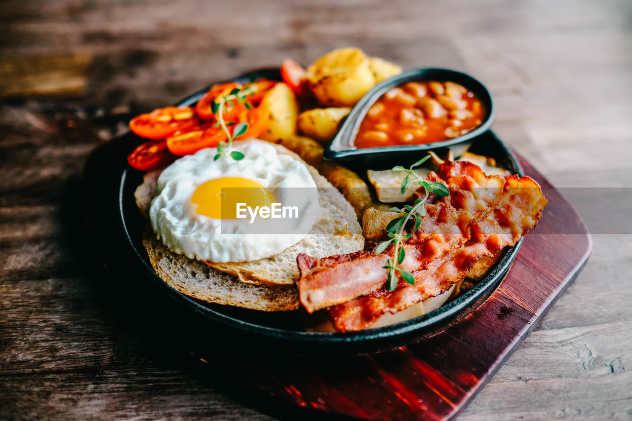 food, food and drink, healthy eating, meal, egg, fried, fried egg, dish, freshness, vegetable, meat, wood, wellbeing, plate, table, breakfast, no people, cuisine, sunny side up, produce, pork, fruit, indoors, tomato, egg yolk, processed meat