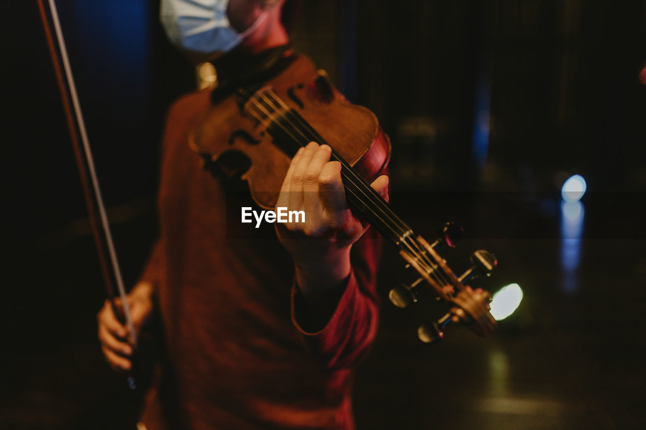 Midsection of man playing violin at music concert