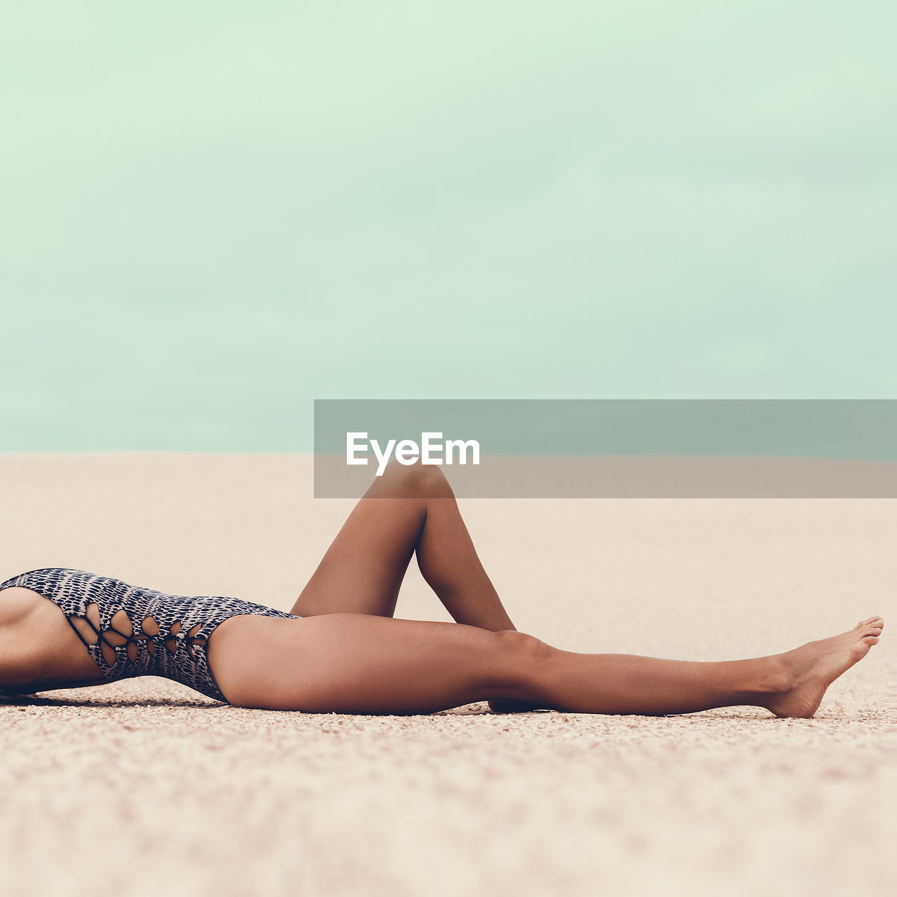 Glamorous tanned lady in a fashionable swimsuit at the beach