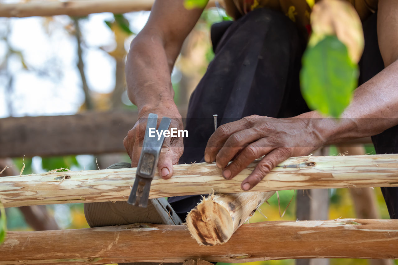 Close-up of a man hammering nails on a eucalyptus wood roof frame. house design using