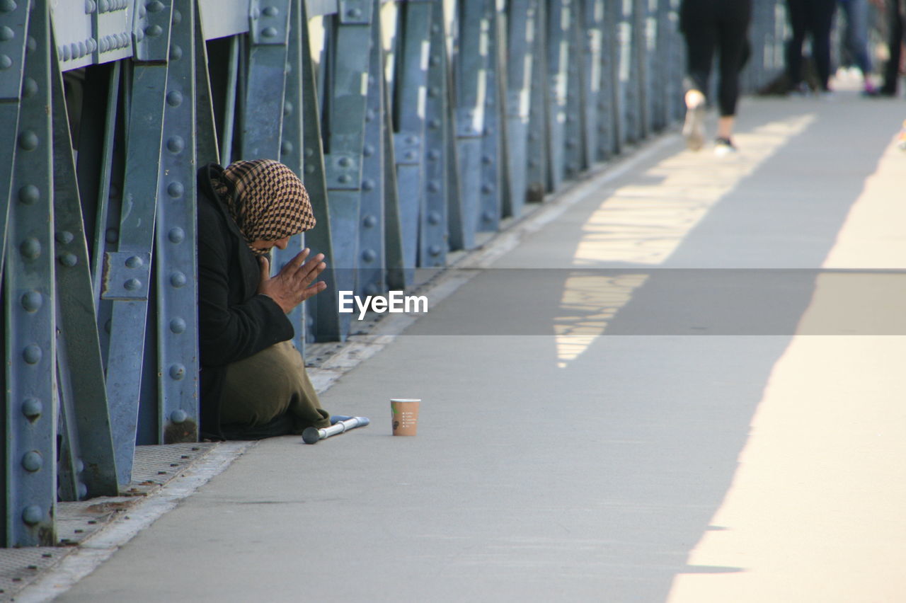 Side view of woman begging on bridge