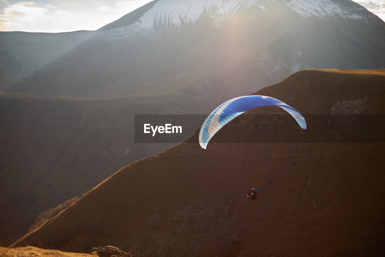 Paraglide silhouette over mountain peaks