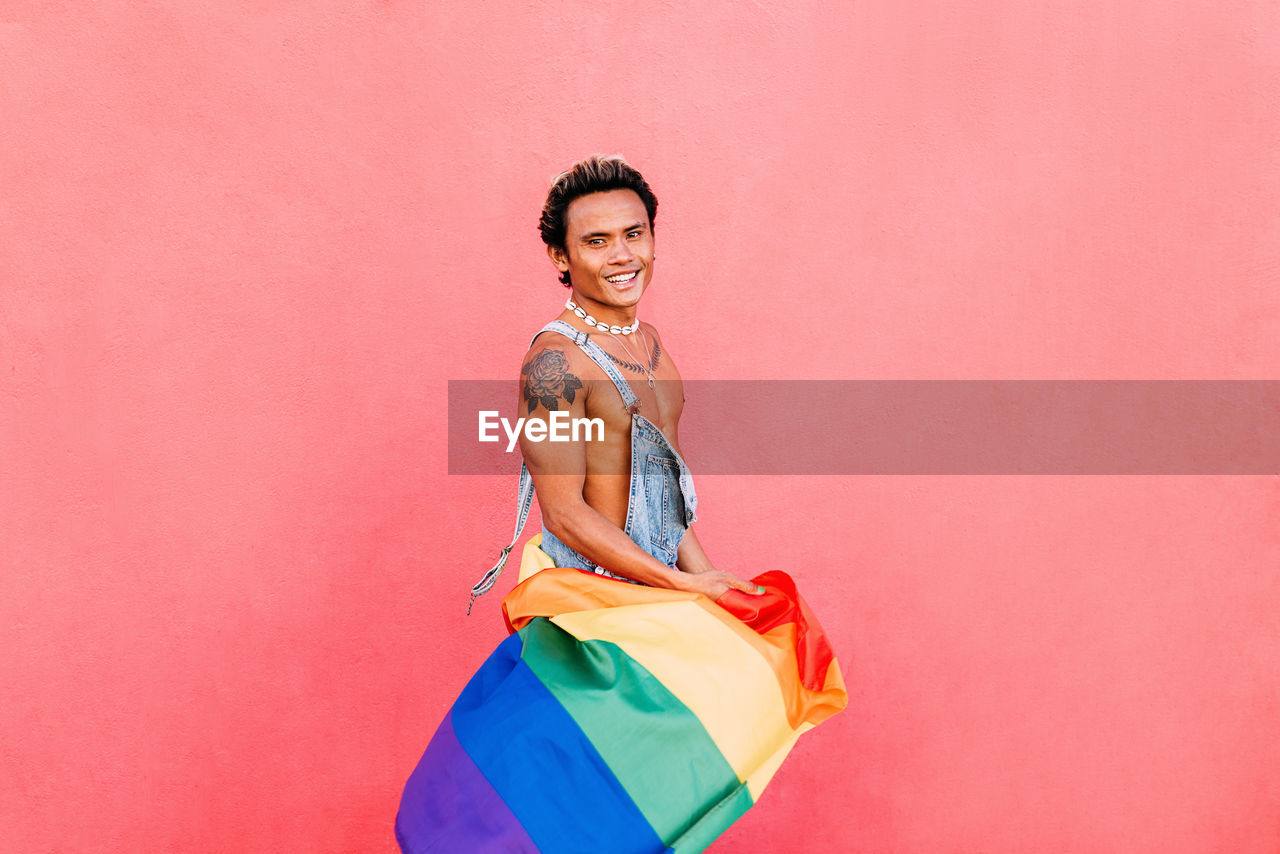 Side view of gay man against pink wall