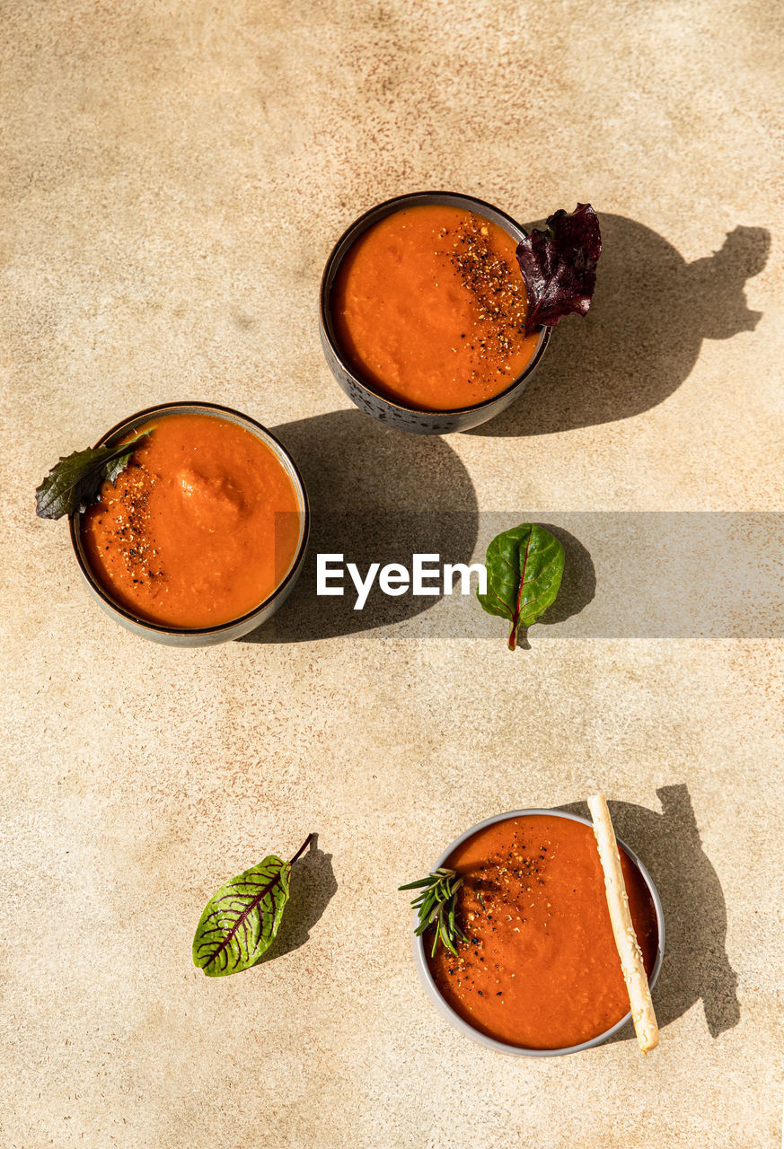 Fresh tomato gazpacho with ground pepper, greens and grissini or bread sticks. 