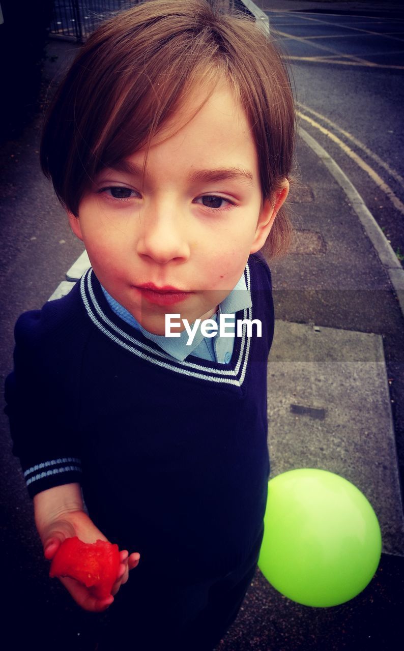 High angle portrait of boy eating while standing on road
